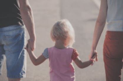 Couple holding a young child by the hands